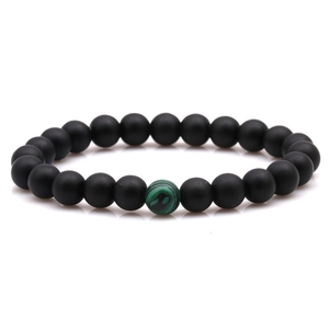 Détail d'un bracelet en pierre noire mate de 8mm avec une perle de malachite verte