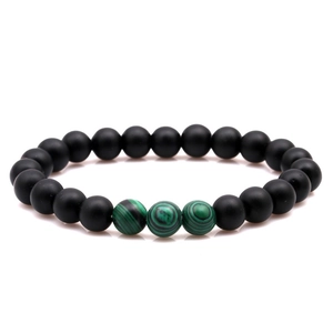 Détail de perles noires mates de 8 mm et de pierres de malachite verte sur un bracelet élastique