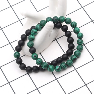 Détail de bracelets en perles de malachite verte et noir mat de 8mm sur main d'exposition