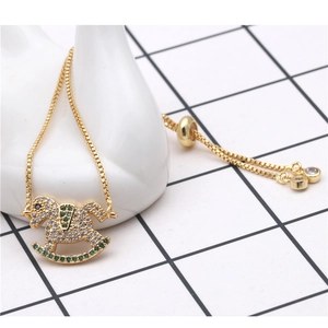 Detalle de pulsera ajustable de cadena box dorada con dije de caballo de balancín
