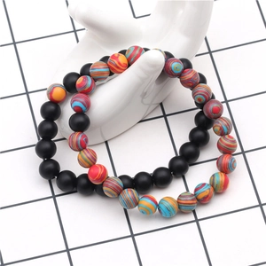 Détail de bracelets en perles noires mates et rayées de 8 mm sur support main en céramique