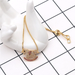 Detalle de una pulsera ajustable de oro con un dije de caballo balancín con circonitas