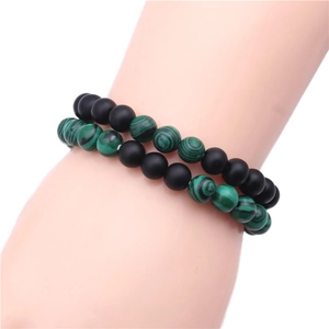 Détail de perles de 8mm en pierre noire mate et malachite verte sur la main d'un mannequin