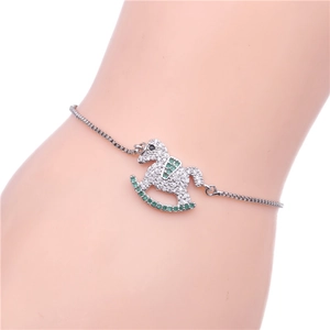 Detalle de una pulsera de caballo balancín con circonitas blancas y gemas verdes