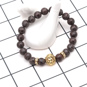 Close-up of brown volcanic stone beads with a golden lion head and crystal spacers