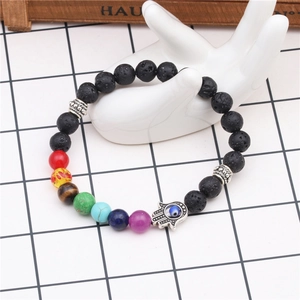 Detailed view of 8mm lava stone chakra bracelet with Hamsa hand charm on a display stand