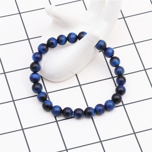 Detail of 8mm deep blue tiger eye stone beads on a white ceramic hand display stand