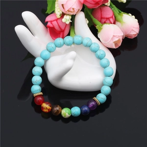 Chakra yoga bracelet with 8mm agate and turquoise beads on a white ceramic hand stand