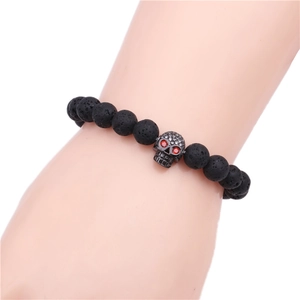 Detail of volcanic stone skull bracelet featuring red crystal eyes and matte black beads
