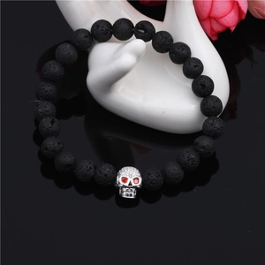 Macro shot of lava stone bracelet with skull charm inlaid with red zircon eyes