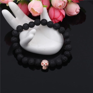 Lava rock bead bracelet featuring a rose gold skull charm with red gemstone eyes