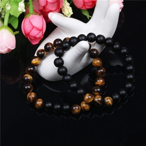 Detailed shot of matte black onyx and tiger eye stone bead bracelets on a hand model