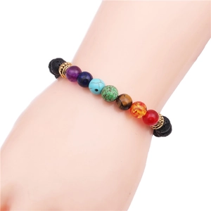 Detail view of 8mm chakra beads and black lava stones on a gold-accented stretch bracelet