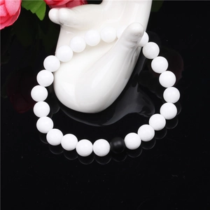 Minimalist 8mm white bead bracelet with a single black onyx stone on a hand display