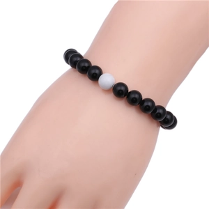 Close-up of 8mm black onyx beads bracelet with a single white turquoise stone on a wrist