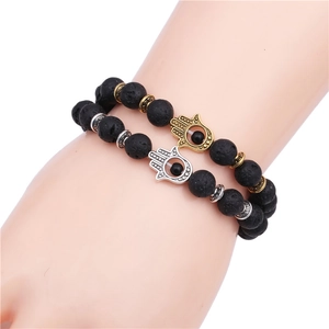 Two-piece 8mm black lava stone bead bracelet set featuring gold and silver Hamsa hand charms