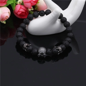 Detailed macro view of 8mm black lava stone beads with skull and crown metal charms