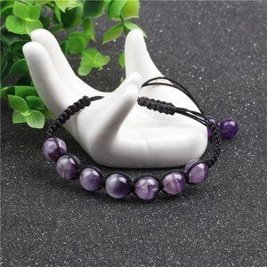 Detail of 10mm amethyst beaded bracelet with hand-woven adjustable cord on ceramic hand