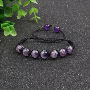 Macro detail of hand-woven bracelet featuring 10mm purple amethyst beads on black cord