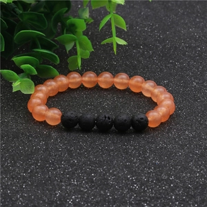 Detalle de cuentas de ágata naranja de 8mm y piedras de lava negra en pulsera elástica