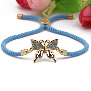 Detail of blue braided bracelet featuring a gold butterfly charm with zircon inlay