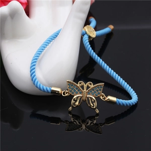 Detail of adjustable blue woven rope bracelet with gold butterfly evil eye charm