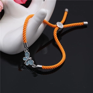 Detail of adjustable orange braided bracelet with blue zircon butterfly pendant on a hand mold