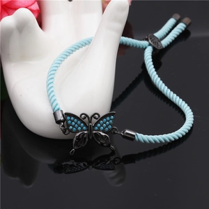 Detail of blue braided bracelet with black butterfly charm on a white ceramic model
