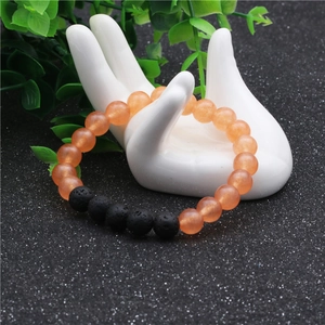 Detalle de cuentas de ágata naranja de 8mm y piedra de lava negra en un soporte de mano