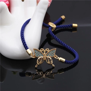 Detail of adjustable blue braided bracelet with golden butterfly pendant on hand model