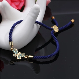 Detailed close-up of blue braided cord bracelet with gold butterfly zircon charm
