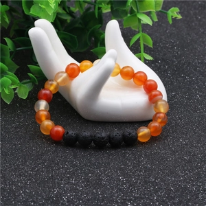 Detalle de cuentas de ágata naranja de 8mm y piedra de lava en soporte de joyas blanco