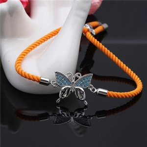 Detail of an orange braided rope bracelet featuring a silver butterfly slider and blue stones