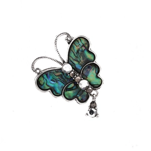 Detailed close-up of a butterfly brooch with iridescent shell wings and sparkling crystals