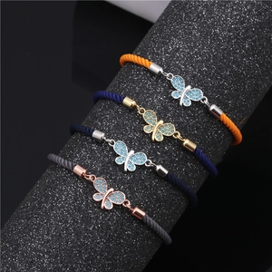 Detail of pavé butterfly bracelets with zircon on woven cords and metal plating