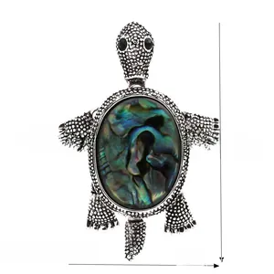 Macro shot of silver turtle brooch featuring iridescent abalone shell inlay and texture
