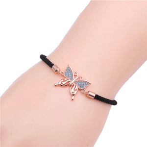 Detail of rose gold butterfly charm bracelet with blue zircon and black woven cord