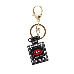 Macro detail of acrylic perfume bottle keychain with checkerboard pattern and kiss me logo