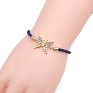 Detail of a copper butterfly bracelet with blue zircons and navy blue woven cord