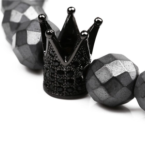 Macro detail of faceted black hematite beads and a micro-pave crown charm on the bracelet