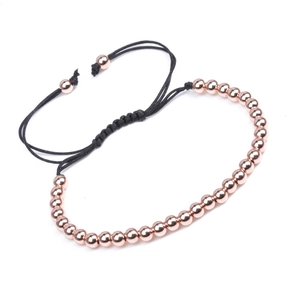 Detail of rose gold beads woven with black adjustable nylon cord on white background
