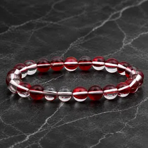 Détail macro du bracelet élastique avec des perles rondes transparentes rouges et blanches