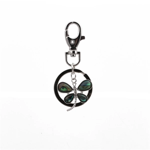 Detailed macro view of silver dragonfly keychain with inlaid abalone shell wings and zircons