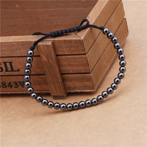 Detail of adjustable black beaded woven bracelet with glossy beads on a wooden texture