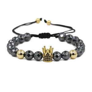 Macro detail of faceted hematite beads and gold crown charm on adjustable cord bracelet