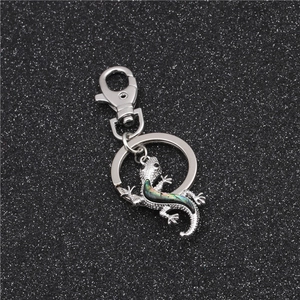 Detailed macro view of a silver gecko keychain with iridescent abalone shell inlay