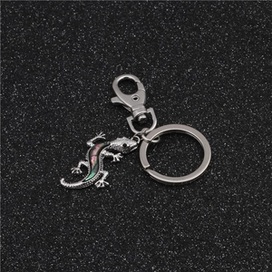 Detailed close-up of a silver gecko keychain with iridescent abalone shell inlay details