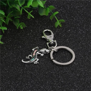 Detailed close-up of a gecko keychain with iridescent abalone shell inlay on metal