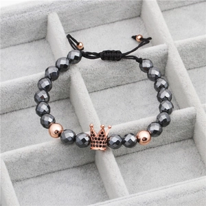 Close-up of faceted black stone beads with rose gold crown charm and adjustable woven cord