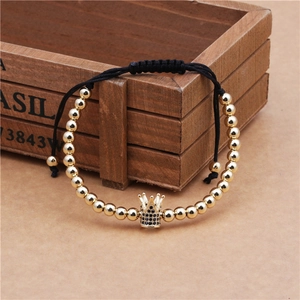 Dettaglio di un bracciale con perline dorate e ciondolo a corona con zirconi neri micro-pave